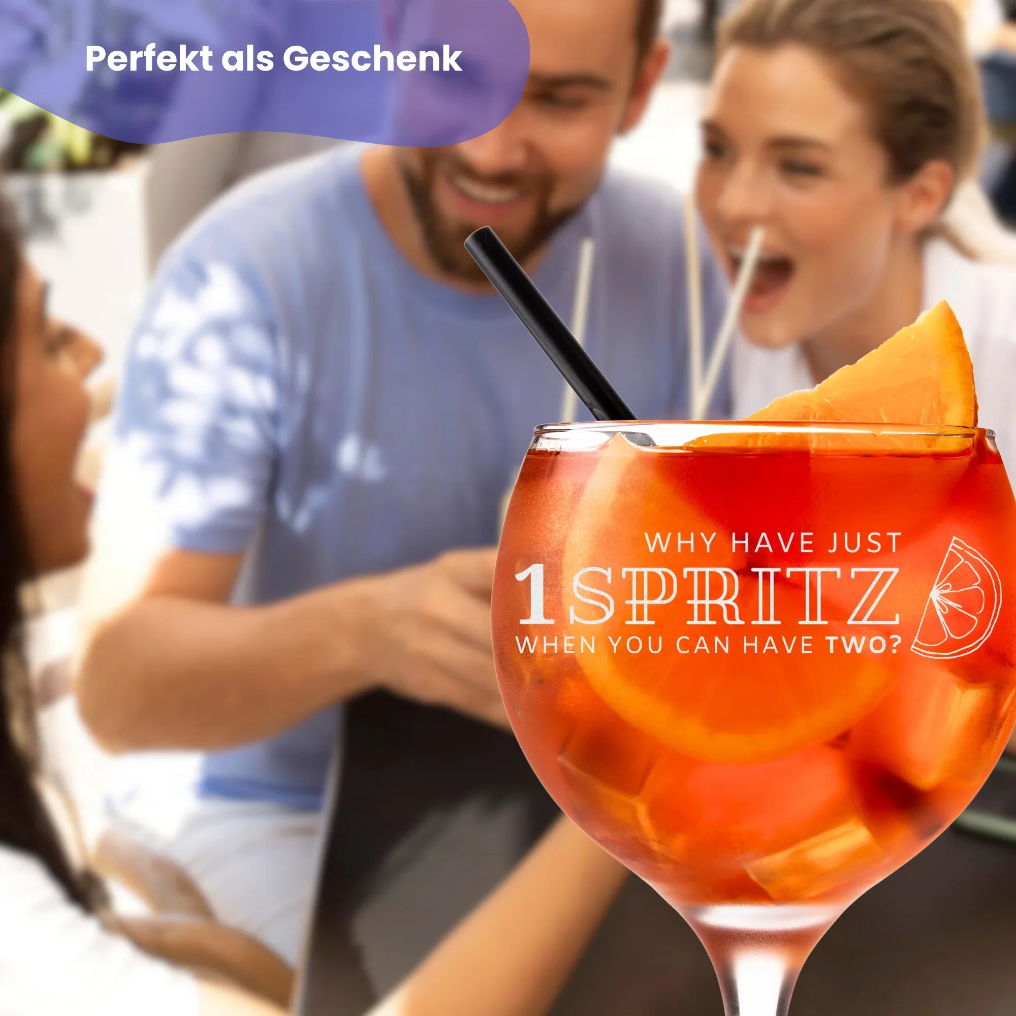 Aperol-Glas mit lustiger Textgravur. Gruppe von Freunden im Hintergrund stehend.