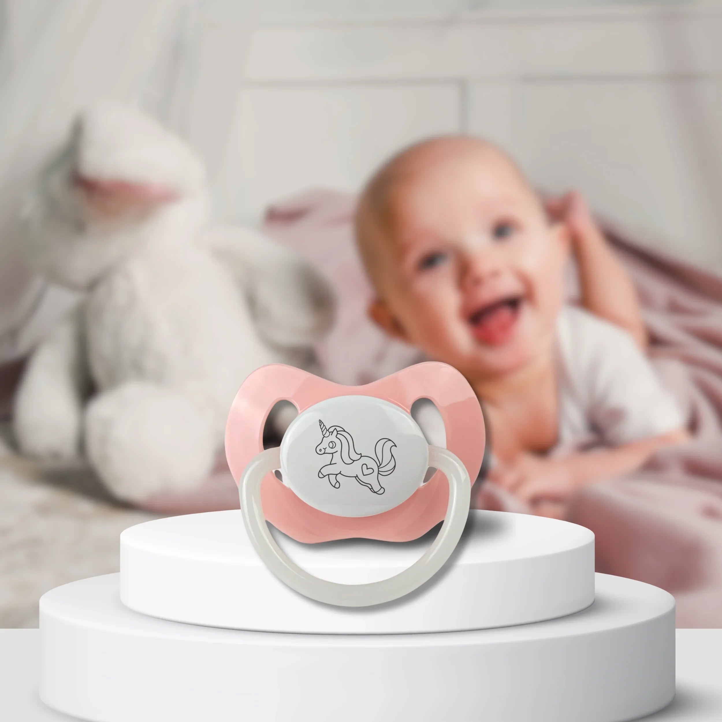 Schnuller rosa mit Gravur Einhorn Baby im Hintergrund
